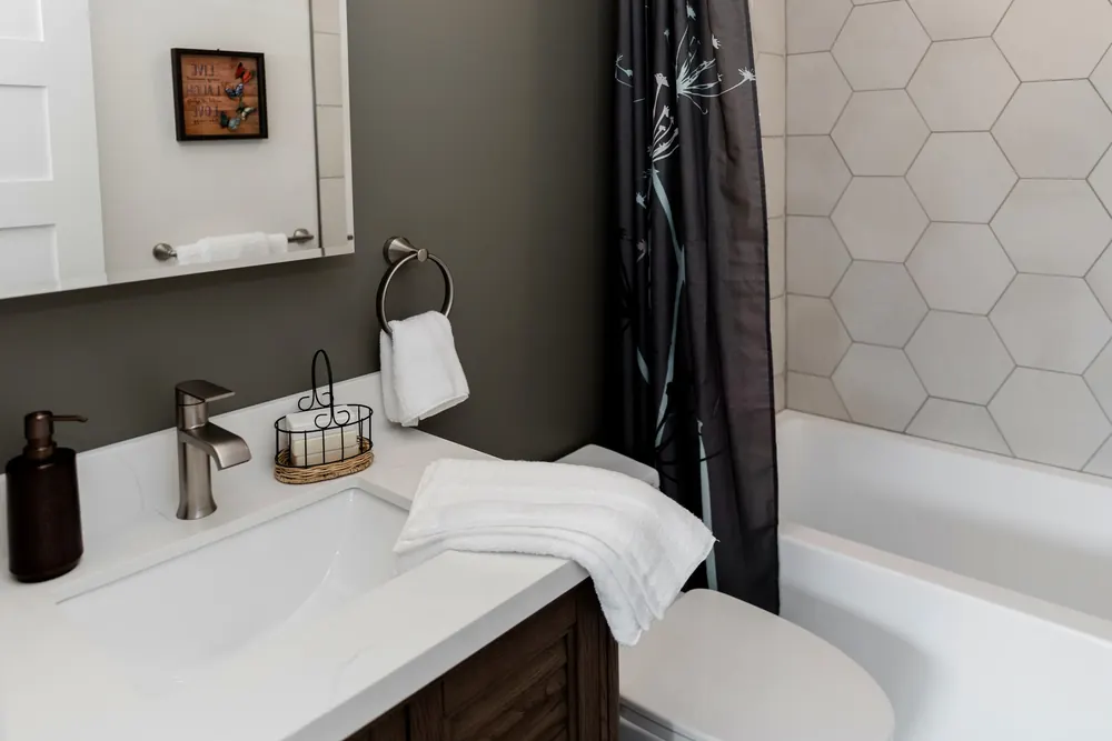 Bathroom vanity with a black faucet beside the tub