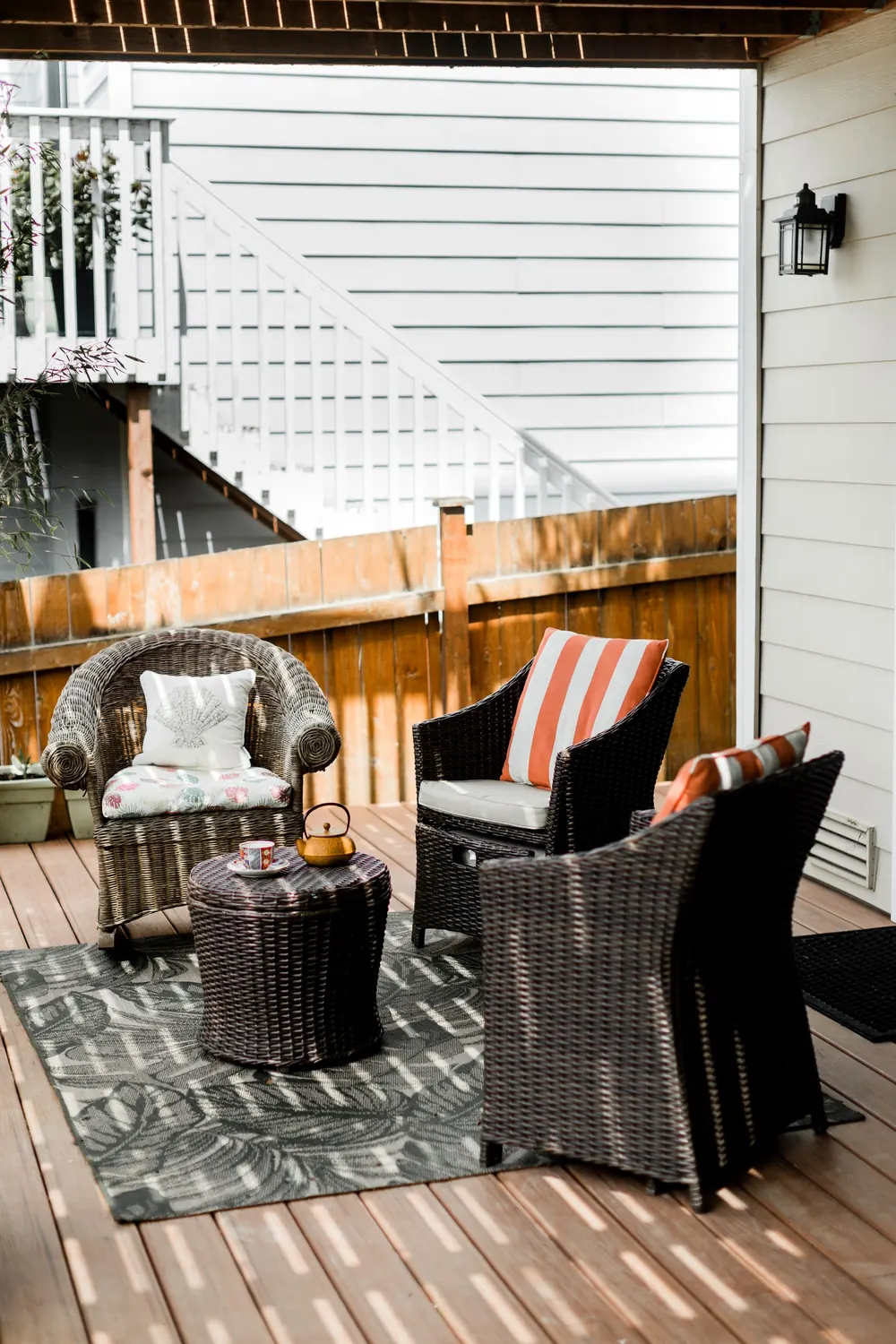 Backyard deck with wicker chairs and an outdoor rug