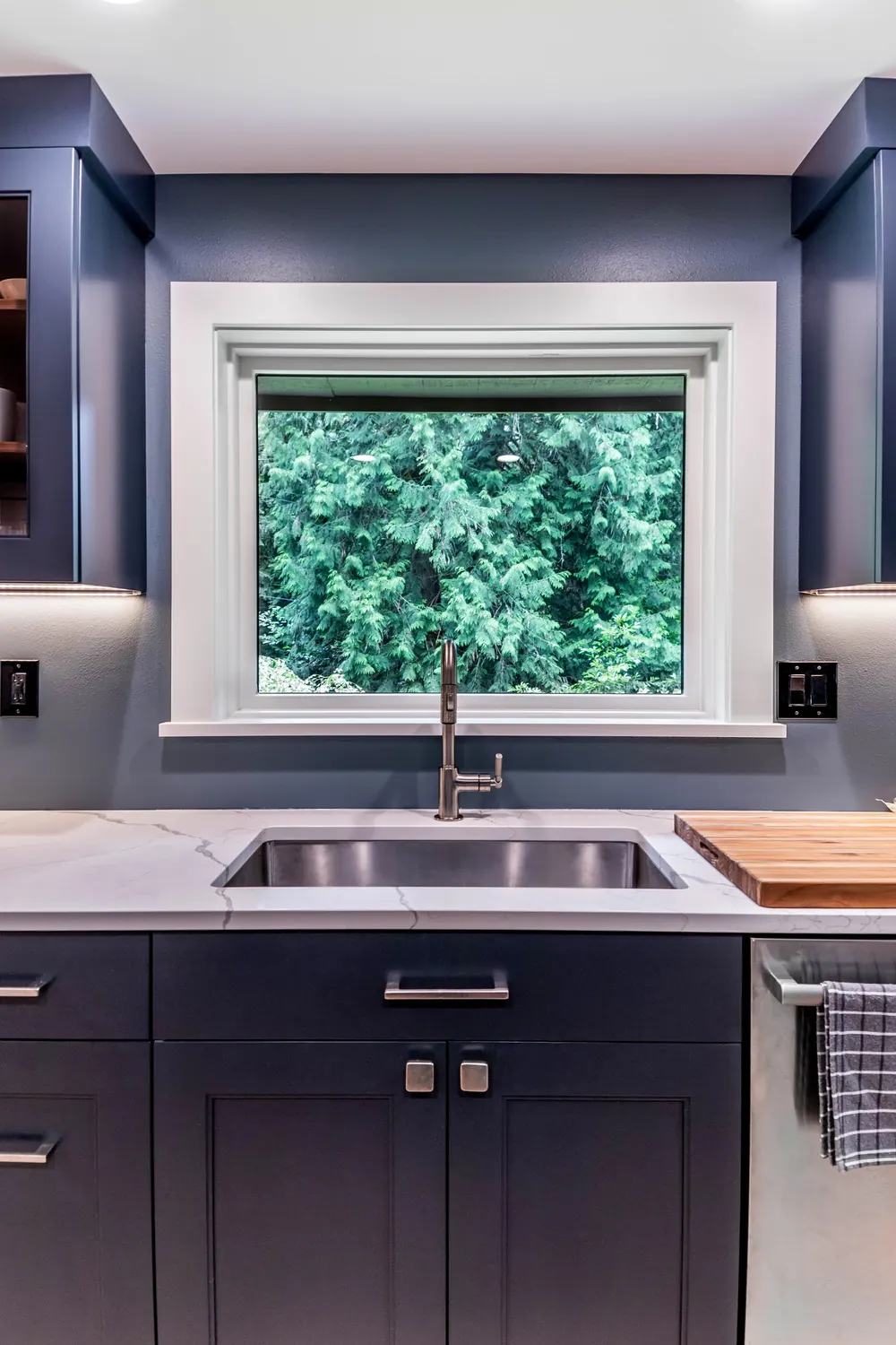 Sink under a window with navy cabinets