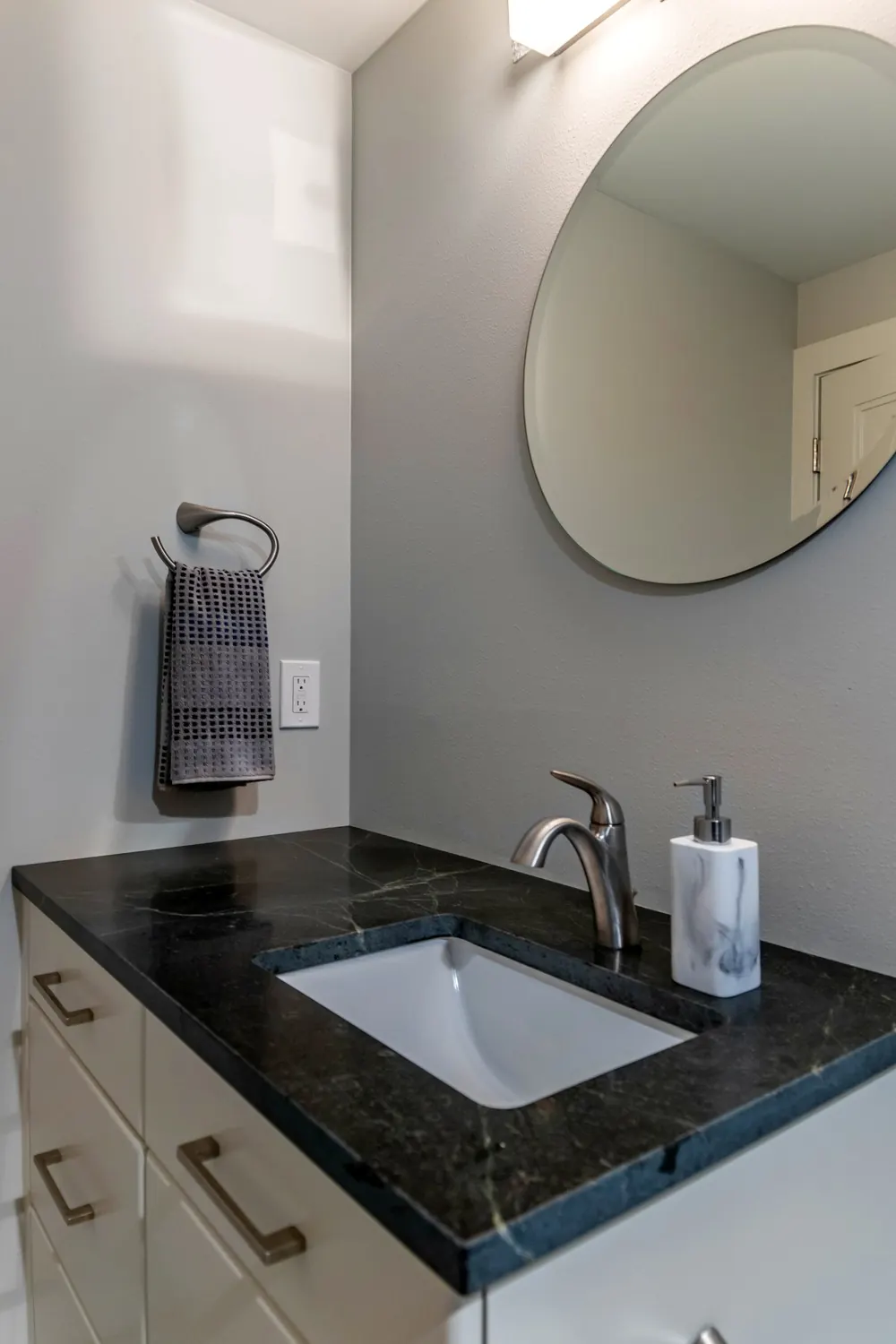 Vanity with a black counter and round mirror