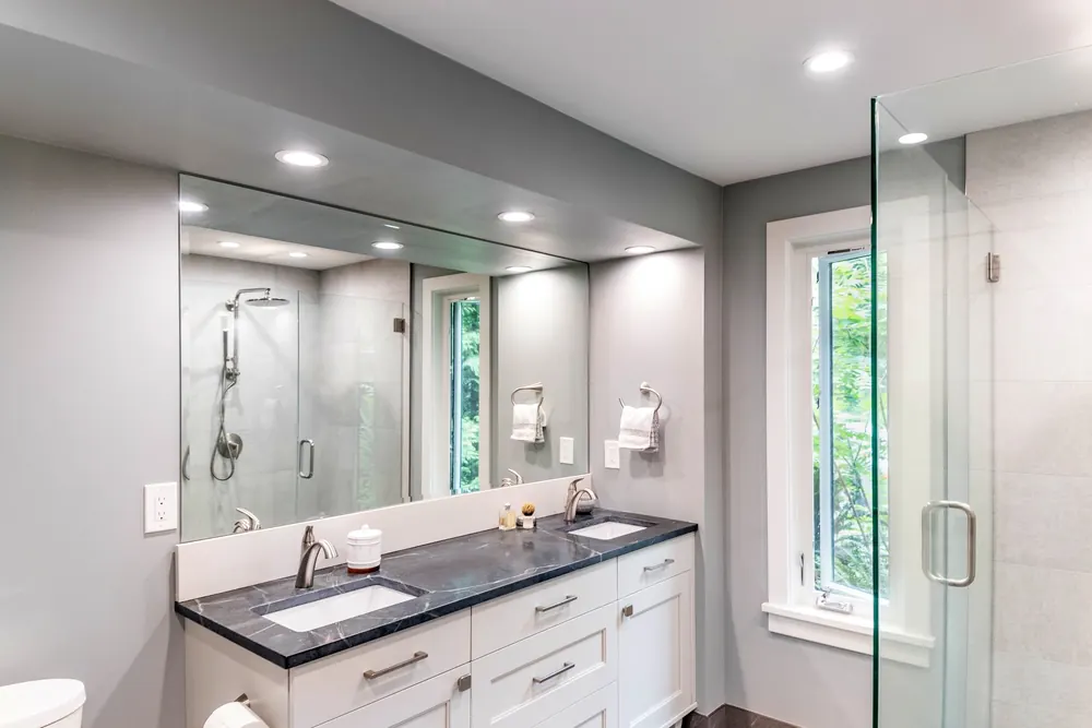 Bathroom with a dark vanity counter and glass shower